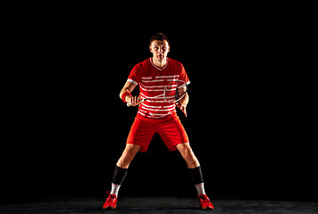 Image showing Young man playing badminton isolated on black studio background