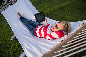 Image showing woman using a tablet computer while relaxing on hammock