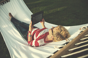 Image showing woman using a tablet computer while relaxing on hammock