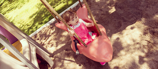 Image showing little girl swinging  on a playground