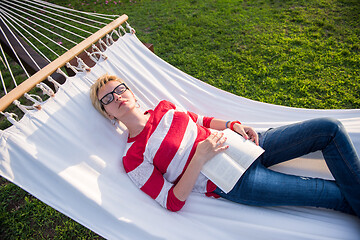 Image showing woman reading a book while relaxing on hammock