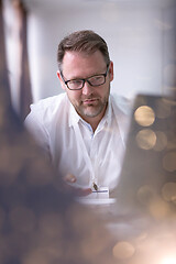 Image showing Business man writing notes while working on laptop