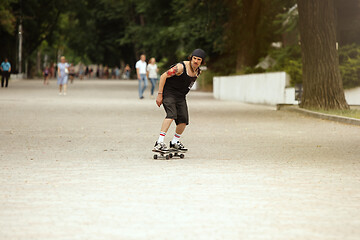 Image showing Skateboarder doing a trick at the city\'s street in cloudly day