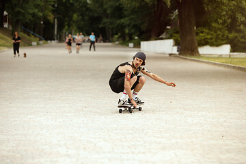 Image showing Skateboarder doing a trick at the city\'s street in cloudly day