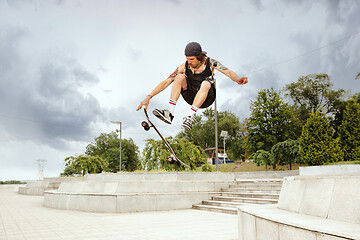 Image showing Skateboarder doing a trick at the city\'s street in cloudly day