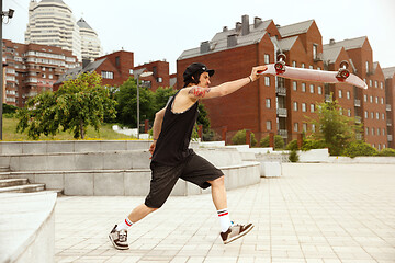 Image showing Skateboarder doing a trick at the city\'s street in cloudly day