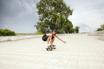 Image showing Skateboarder doing a trick at the city\'s street in cloudly day