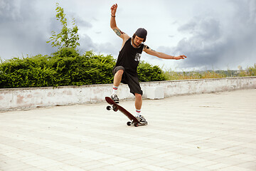 Image showing Skateboarder doing a trick at the city\'s street in cloudly day