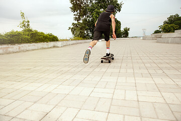 Image showing Skateboarder doing a trick at the city\'s street in cloudly day