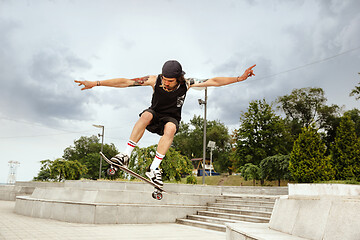 Image showing Skateboarder doing a trick at the city\'s street in cloudly day