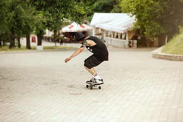 Image showing Skateboarder doing a trick at the city\'s street in cloudly day