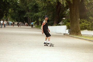 Image showing Skateboarder doing a trick at the city\'s street in cloudly day