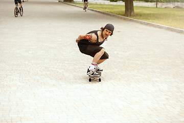 Image showing Skateboarder doing a trick at the city\'s street in cloudly day