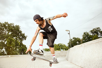 Image showing Skateboarder doing a trick at the city\'s street in cloudly day