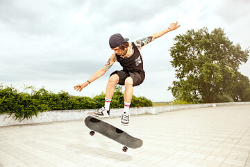 Image showing Skateboarder doing a trick at the city\'s street in cloudly day