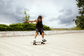 Image showing Skateboarder doing a trick at the city\'s street in cloudly day