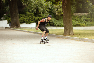 Image showing Skateboarder doing a trick at the city\'s street in cloudly day