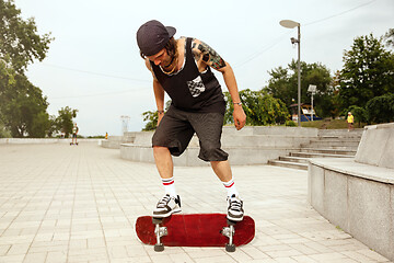 Image showing Skateboarder doing a trick at the city\'s street in cloudly day