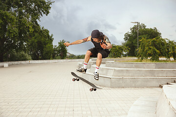 Image showing Skateboarder doing a trick at the city\'s street in cloudly day