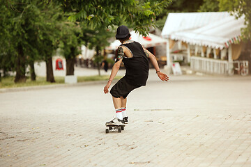 Image showing Skateboarder doing a trick at the city\'s street in cloudly day