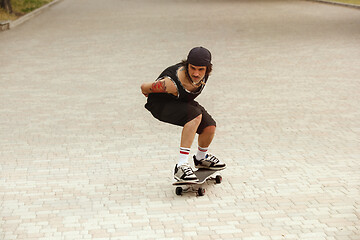 Image showing Skateboarder doing a trick at the city\'s street in cloudly day