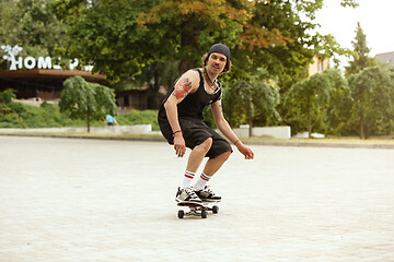 Image showing Skateboarder doing a trick at the city\'s street in cloudly day