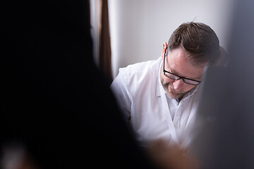 Image showing Business man writing notes while working on laptop