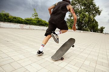 Image showing Skateboarder doing a trick at the city\'s street in cloudly day