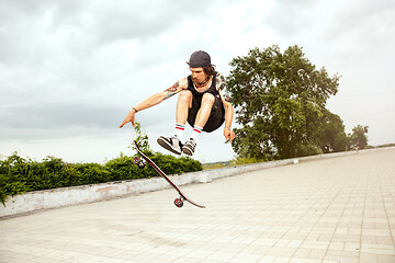 Image showing Skateboarder doing a trick at the city\'s street in cloudly day