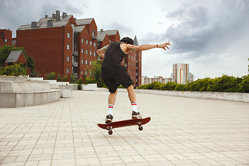 Image showing Skateboarder doing a trick at the city\'s street in cloudly day