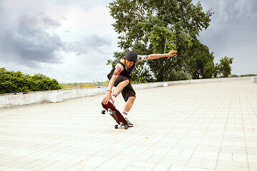 Image showing Skateboarder doing a trick at the city\'s street in cloudly day