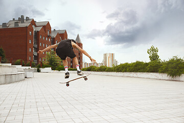 Image showing Skateboarder doing a trick at the city\'s street in cloudly day