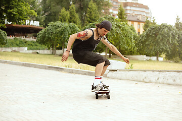 Image showing Skateboarder doing a trick at the city\'s street in cloudly day