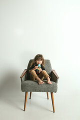 Image showing Little child sitting and playing in armchair on white studio background