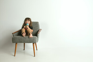 Image showing Little child sitting and playing in armchair on white studio background