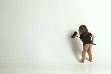 Image showing Little child sitting and playing in armchair on white studio background