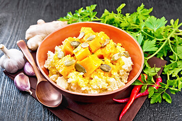 Image showing Porridge millet with spicy pumpkin in clay bowl on wooden board