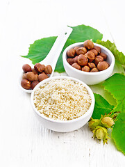 Image showing Flour and hazelnuts in bowls on light wooden board