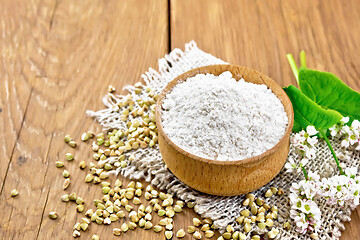 Image showing Flour buckwheat green in bowl with flowers and leaves on board