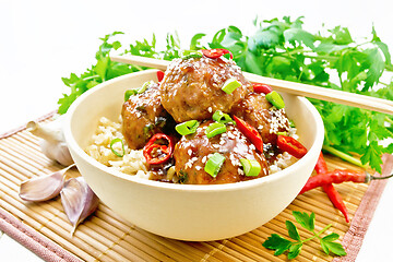 Image showing Meatballs in sweet and sour sauce with rice on light wooden boar