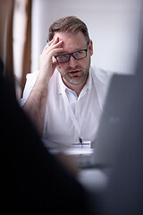 Image showing Business man writing notes while working on laptop