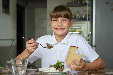 Image showing Happy girl happily eats the second dish and looks into the frame with a cute smile