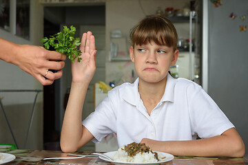 Image showing The girl does not want to eat fresh herbs at lunch