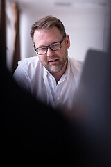 Image showing Business man writing notes while working on laptop