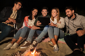 Image showing friends with tablet pc at fire on beach at night