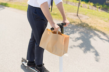 Image showing businessman with takeaway paper bag riding scooter