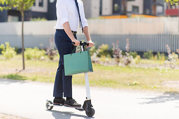 Image showing businessman with shopping bag riding scooter