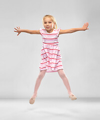 Image showing happy little girl in striped dress jumping