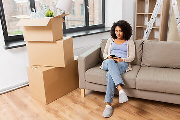 Image showing woman with smartphone and boxes moving to new home