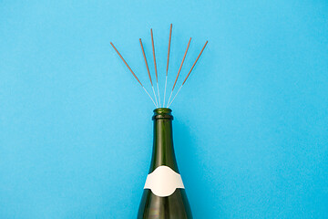 Image showing champagne bottle with sparklers on blue